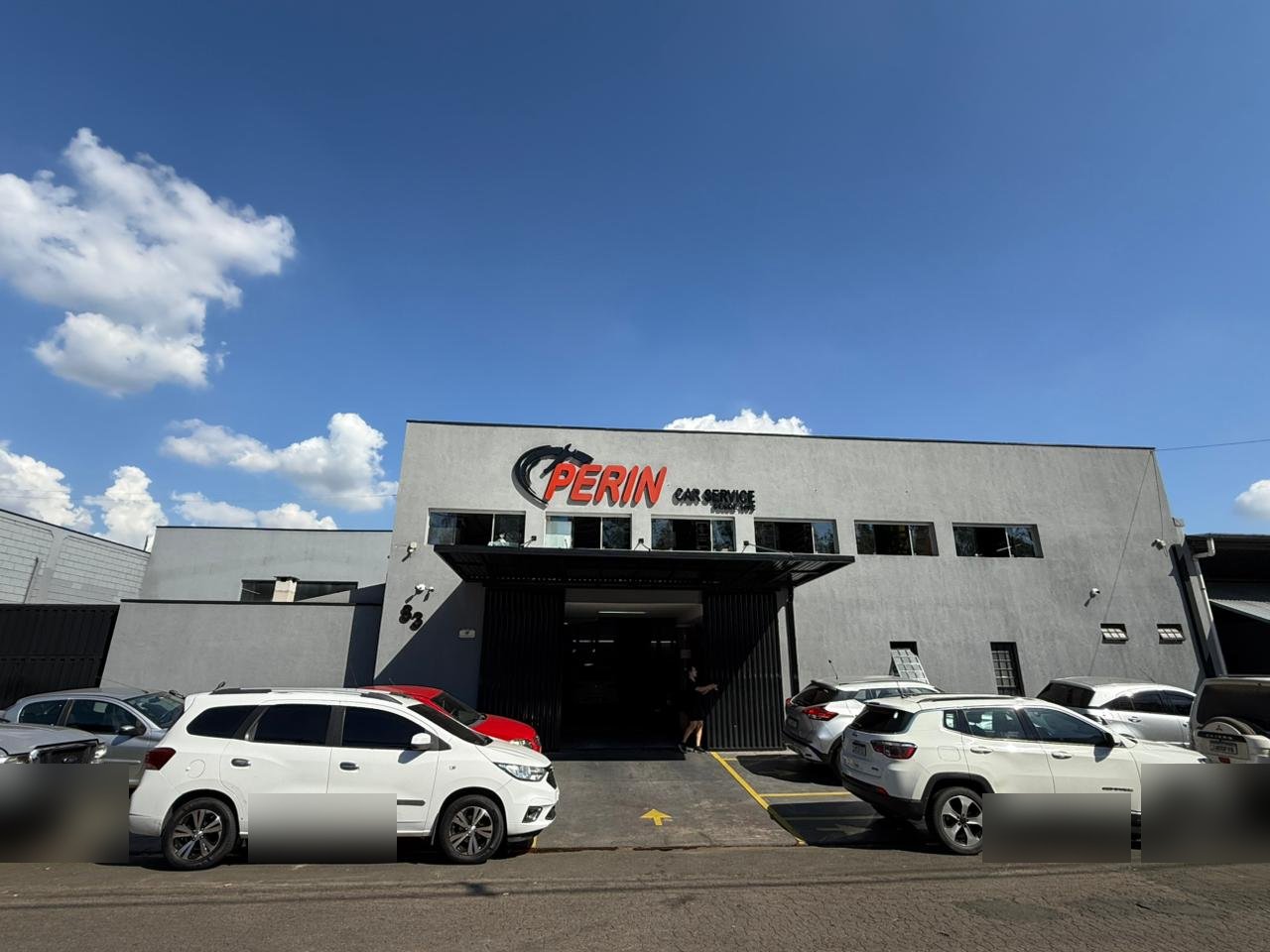 Vista geral da oficina Perin Car Service mostrando múltiplos veículos em atendimento